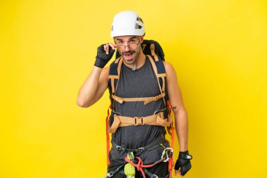 Kafkasyalı genç dağcı sarı arka planda gözlüklü ve mutlu.