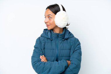 Beyaz arka plana izole edilmiş, kış kulaklığı takan genç İspanyol kadın.