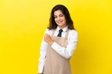 Genç Kafkas lokantası garsonu sarı arka planda zaferi kutluyor.