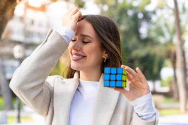 Dışarıda elinde üç boyutlu bir bulmaca kübü tutan güzel bir kadın bir şeyin farkına vardı ve çözümü amaçladı.
