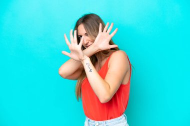 Mavi arka planda izole edilmiş genç beyaz kadın ellerini öne uzatıyor.