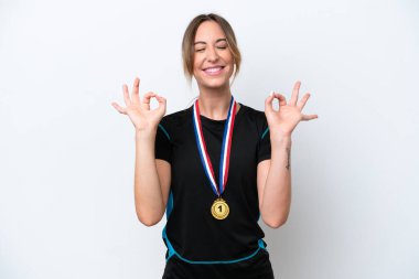 Zen pozisyonunda beyaz arka planda madalyaları olan beyaz bir kadın.