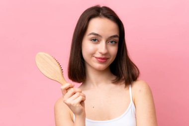 Genç Ukraynalı kadın pembe arka planda saç tarağıyla izole edilmiş.