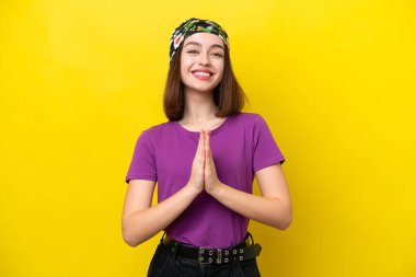 Sarı arka planda izole edilmiş genç Ukraynalı kadın avuç içlerini bir arada tutuyor. İnsan bir şey ister.