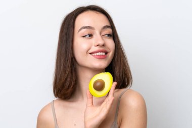 Genç Ukraynalı bir kadın beyaz arka planda izole edilmiş, elinde avakado tutarken gülümsüyor. Portreyi kapat