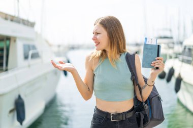 Dışarıda pasaportu olan sarışın genç bir kadın, yüzünde sürpriz bir ifade var.