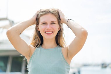 Açık havada genç sarışın bir kadın Neşeli bir ifadeyle