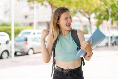Genç sarışın bayan açık havada zaferi kutluyor.