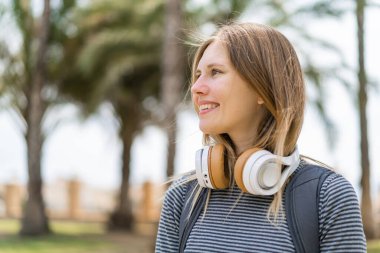 Açık havada genç sarışın bir kadın Neşeli bir ifadeyle