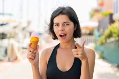 Açık havada kornet dondurması olan genç, güzel Bulgar kadın şaşırmış ve ön tarafı işaret ediyor.