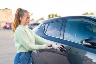 Dışarıda arabanın anahtarlarını tutan genç ve güzel bir kız.