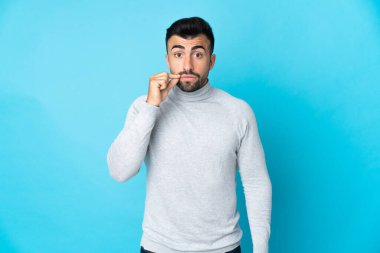İzole edilmiş mavi arka planda beyaz bir adam sessizlik işareti gösteriyor.