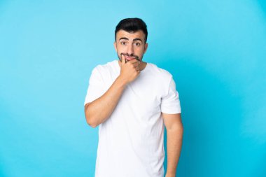 İzole edilmiş mavi arka planda beyaz bir adamın şüpheleri var.
