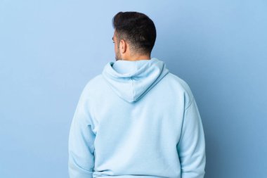 Kafkasyalı adam mavi arka planda izole edilmiş ve yana bakıyor.