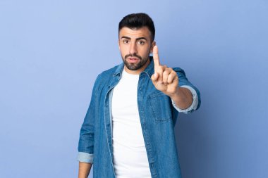 İzole edilmiş mavi arka plan üzerinde beyaz bir adam ciddi bir ifadeye sahip birini sayıyor.