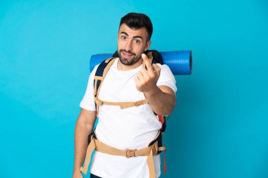 Genç dağcı, soyutlanmış mavi arka planda geliyor.