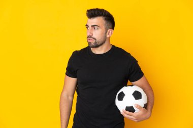 Futbol topuyla izole edilmiş sarı arka planda beyaz bir adam.