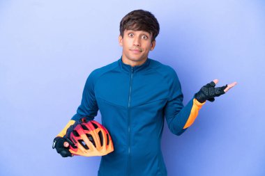 Mor arka planda izole edilmiş genç beyaz adam ellerini kaldırırken şüpheleri var.