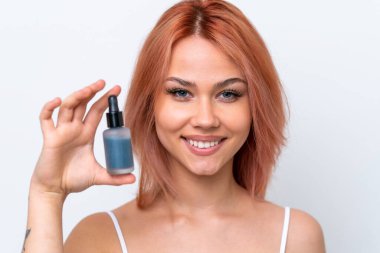 Beyaz arka planda izole edilmiş genç bir Rus kızı elinde bir serum tutarken gülümsüyor. Portreyi kapat