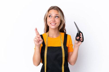 Beyaz arka planda izole edilmiş genç Rus terzi kız parmaklarını çapraz yapıp en iyisini diliyor.