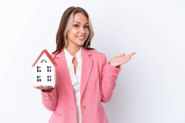 Rus emlakçı, beyaz arka planda izole edilmiş bir oyuncak evi tutuyor. Davet edilmeyi bekliyor.