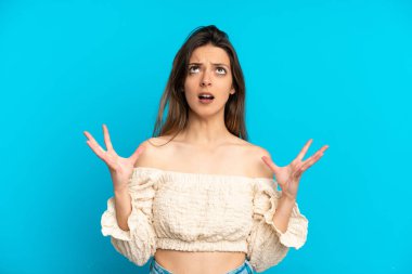 Mavi arka planda izole edilmiş genç beyaz kadın bunalımda.