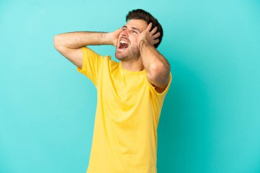 Mavi arka planda izole edilmiş beyaz, yakışıklı genç bir adam bunalımda.