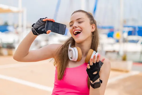 Молодая Красивая Спортивная Девушка Открытом Воздухе Помощью Мобильного Телефона Пения — стоковое фото