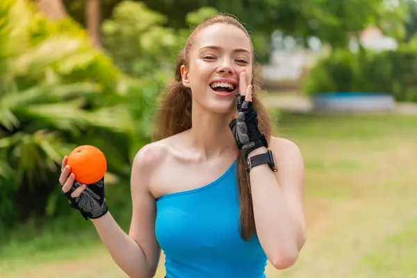 Young Pretty Sport Girl Holding Orange Outdoors Shouting Mouth Wide — Stock Photo, Image