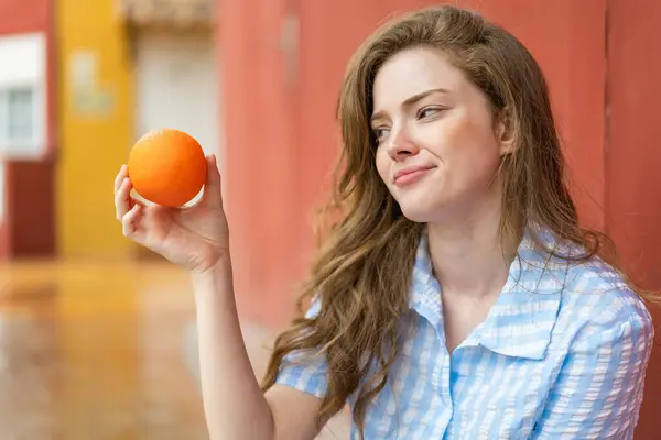 Młoda Ruda Kobieta Zewnątrz Trzymając Pomarańczę — Zdjęcie stockowe