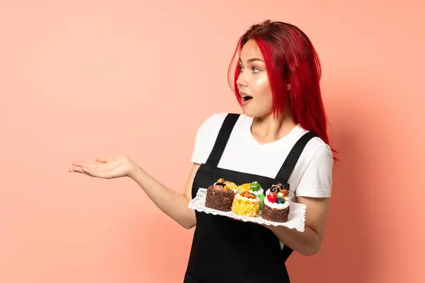 Konditor Hält Muffins Isoliert Auf Rosa Hintergrund Mit Überraschendem Gesichtsausdruck — Stockfoto