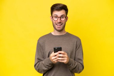 Sarı arka planda izole genç beyaz adam şaşırdı ve bir mesaj gönderiyor.