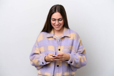 Beyaz arka planda izole edilmiş genç bir kız cep telefonuyla mesaj gönderiyor.