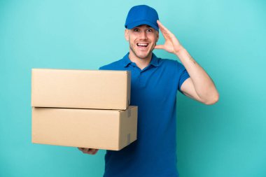 Teslimatçı beyaz adam mavi arka planda, sürpriz bir ifadeyle izole edilmiş.