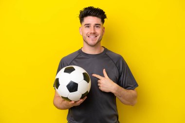 Yakışıklı genç futbolcu, sarı arka planda izole edilmiş, şaşırmış bir yüz ifadesi var.