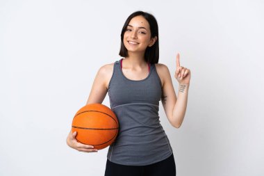 Beyaz arka planda izole edilmiş basketbol oynayan genç bir kadın harika bir fikre işaret ediyor.