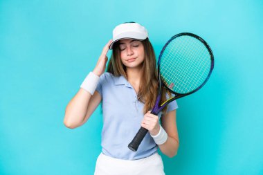 Genç tenisçi kadın mavi arka planda izole edilmiş, baş ağrısı var.