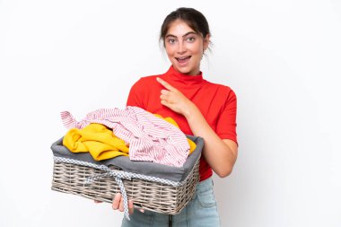 Beyaz arka planda izole edilmiş çamaşır sepeti tutan beyaz bir kadın bir ürünü sunmak için kenarı işaret ediyor.