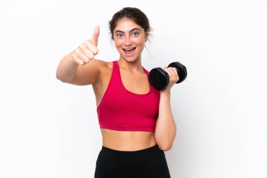 Beyaz arka planda halter kaldıran beyaz tenli genç bir kadın. Baş parmakları havada. Çünkü iyi bir şey oldu.