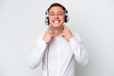 Telemarketer Brazilian man working with a headset isolated on white background smiling with a happy and pleasant expression