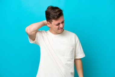 Genç ve yakışıklı Brezilyalı bir adam mavi arka planda izole edilmiş ve boynu ağrıyor.