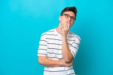 Genç ve yakışıklı Brezilyalı bir adam mavi arka planda izole edilmiş.