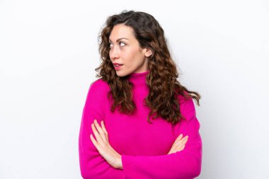 Beyaz arka planda izole edilmiş genç beyaz kadın yan tarafa bakıyor.