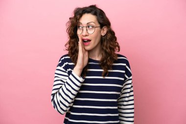 Pembe arka planda soyutlanmış beyaz bir kadın. Yan tarafa bakarken sürpriz bir jest yapıyor.