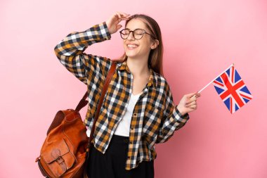 Birleşik Krallık bayrağını elinde tutan genç İspanyol kadın pembe arka planda izole edilmiş, çok gülümsüyor.