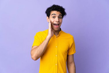 Genç Venezuelalı adam mor arka planda izole edilmiş, şaşırmış ve şok olmuş bir yüz ifadesi var.