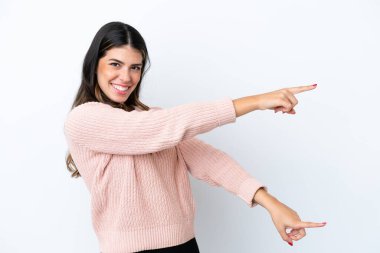 Beyaz arka planda izole edilmiş genç bir İtalyan kadın parmak işareti yapıyor ve bir ürün sunuyor.