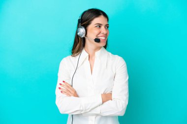 Tele pazarlamacı İtalyan kadın mavi arka planda izole edilmiş bir kulaklıkla çalışıyor.