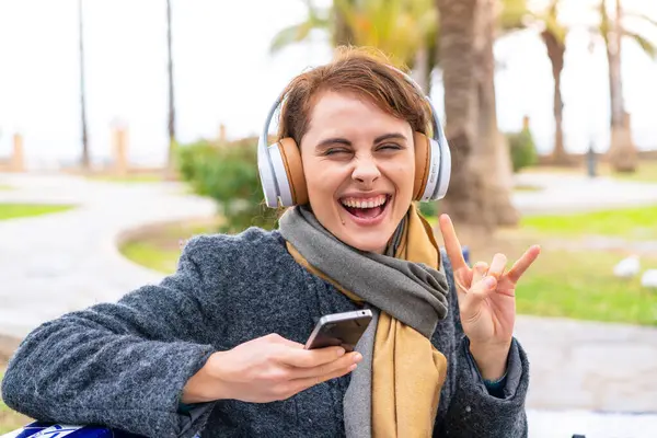 Brunette Woman Outdoors Listening Music Mobile Making Rock Gesture — Stock Photo, Image