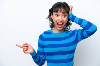 Beyaz arka planda izole edilmiş genç Arjantinli kadın şaşırdı ve parmağını yana çevirdi.